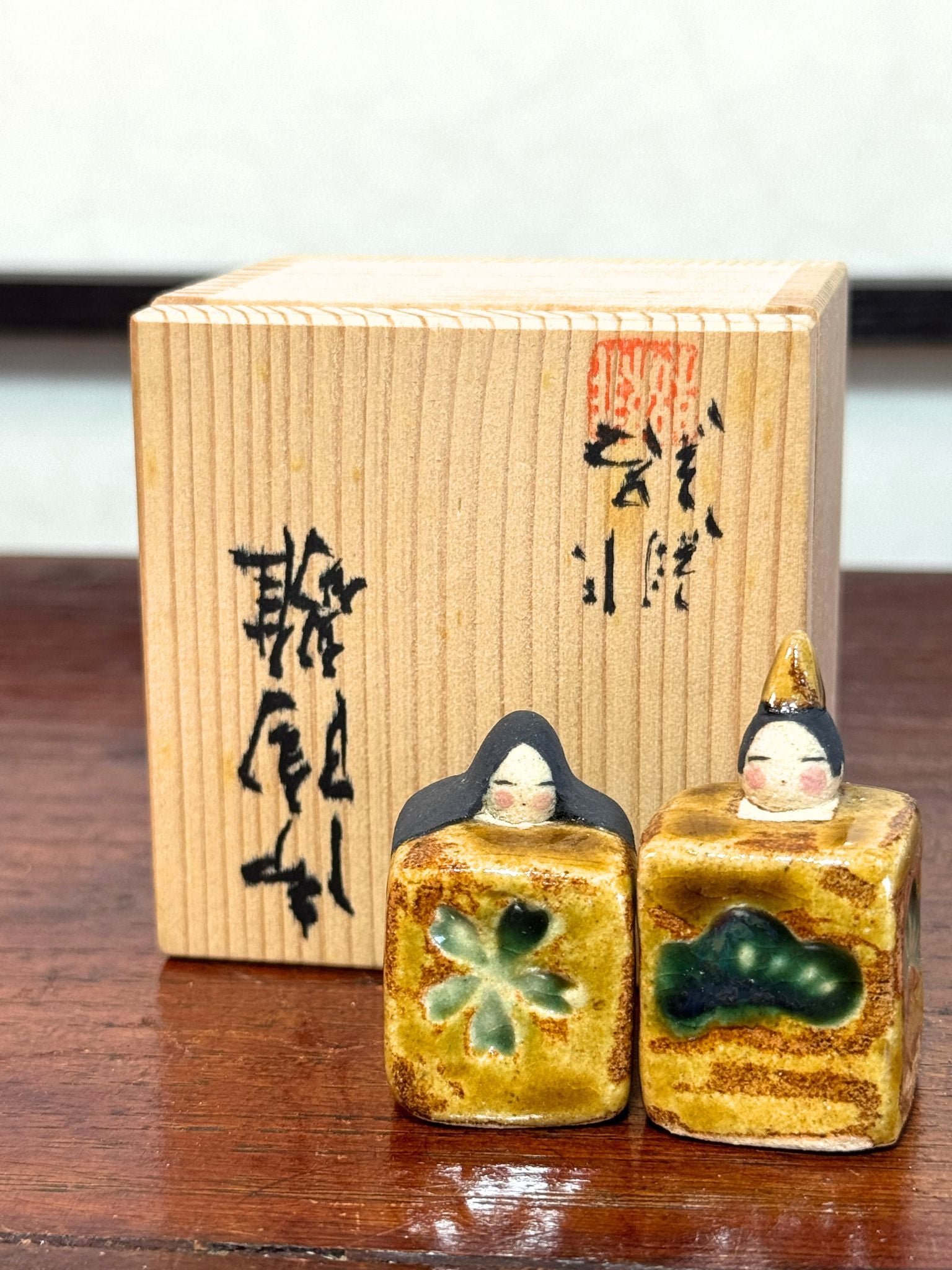 couple de poupées impériales japonaises cubiques en céramique émaillée devant boîte en bois