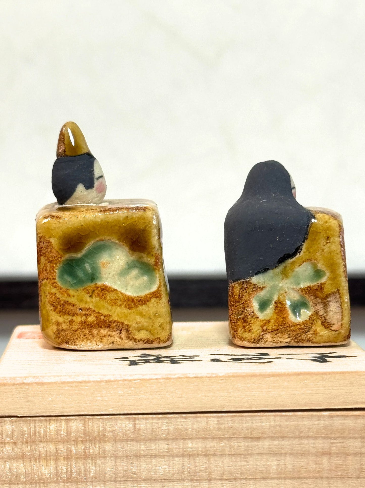 couple de poupées impériales japonaises cubiques en céramique émaillée sur boîte en bois, vu du profil droit