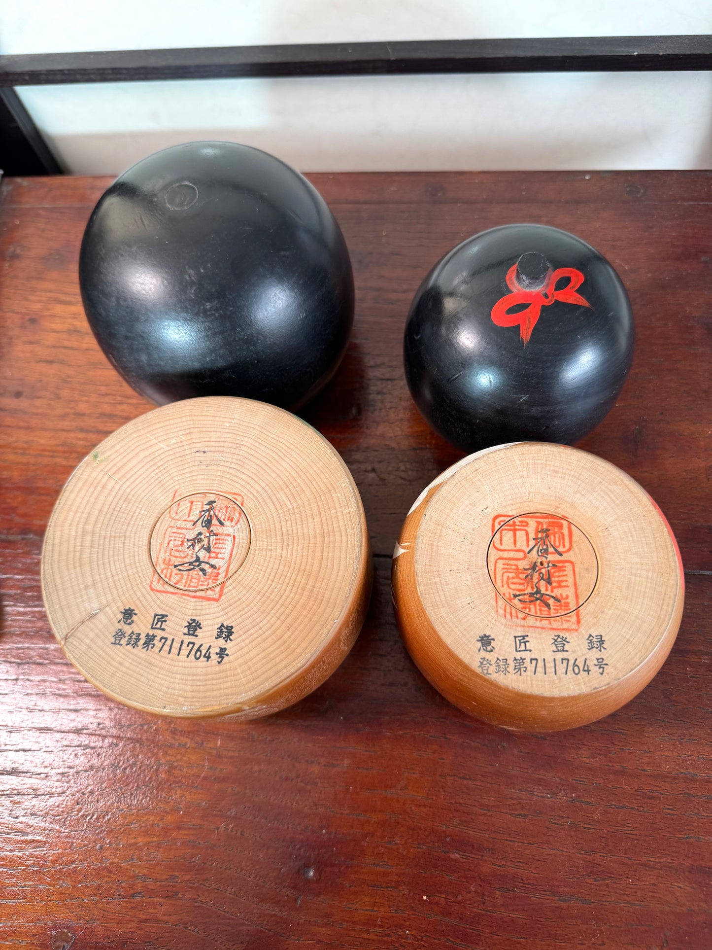 Couple de kokeshi rieuses en bois, calligraphie rouge et verte, signées Sato Kouson, signature sur le dessous