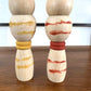 kokeshi, poupée japonaise en bois, couple avec ceinture rouge pour la femme et jaune pour l'homme, gros plan sur les corps peints