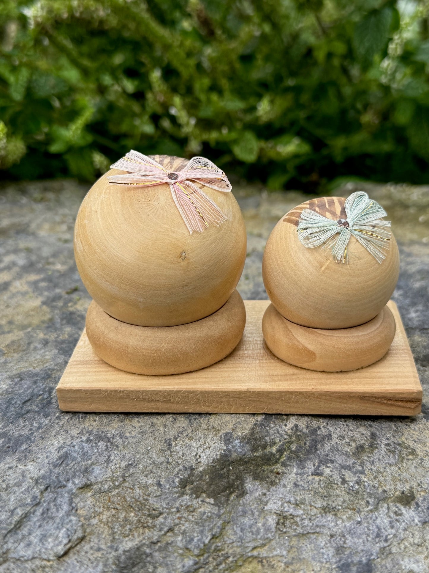 Couple de poupées kokeshi en bois sur socle, avec rubans rose et vert vue de dos