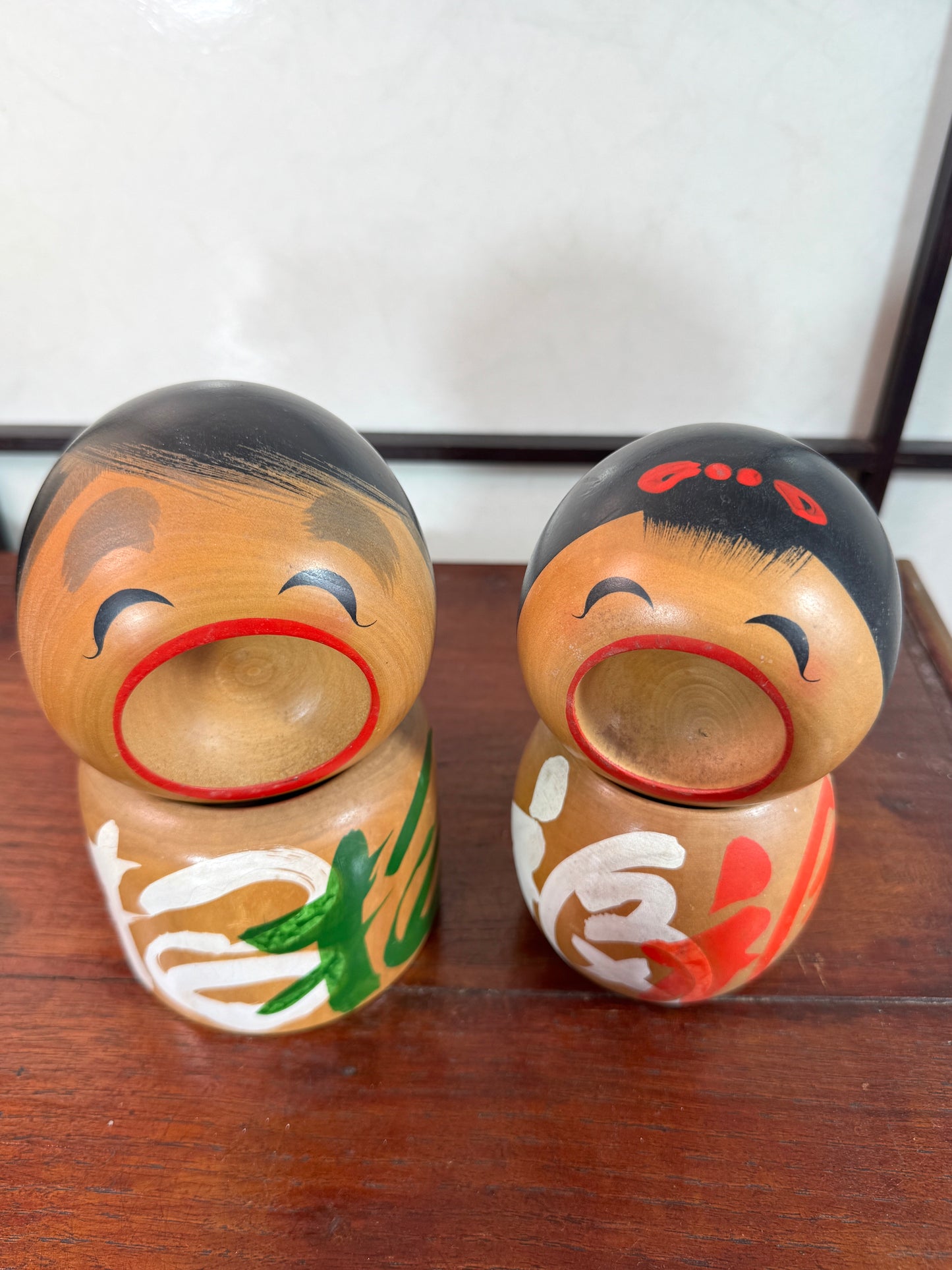 Couple de kokeshi rieuse sato verte et rouge vue dessus
