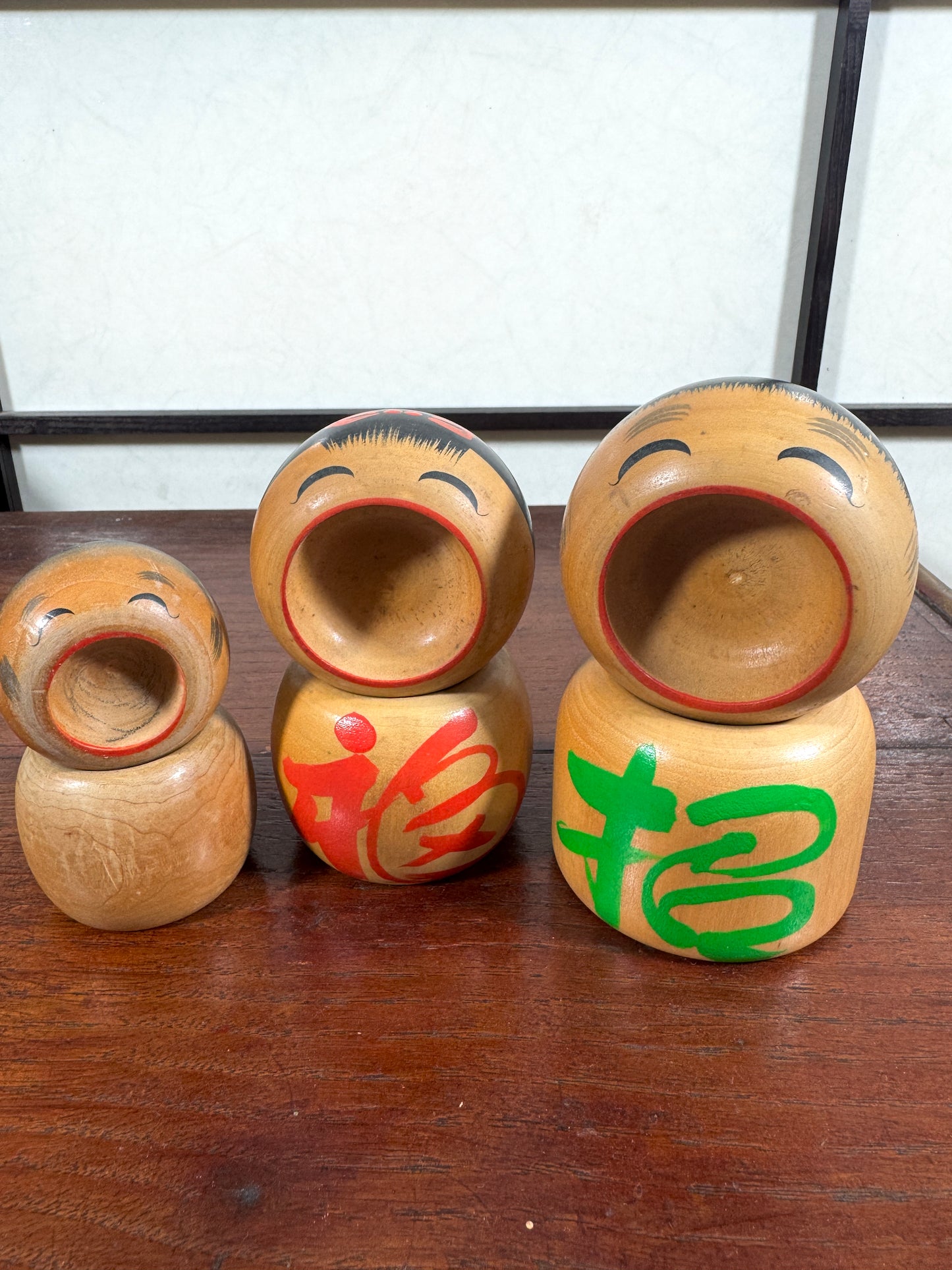Trio de kokeshi en bois riant aux éclats avec calligraphie rouge et verte de Sato Kouson