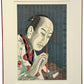 Estampe japonaise contemporaine de Tsuruya Kōkei représentant le portrait d’Utamaro en train de peindre, tenant un pinceau rouge sur fond calligraphié, avec encadrement en sous-verre bordé rouge.