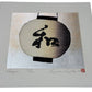 estampe japonaise de Kunio Kaneko représentant une lanterne japonaise ronde et blanche avec l'inscription nagomi en kanji, sur fond or et argent, le reflet du fond vu de profil