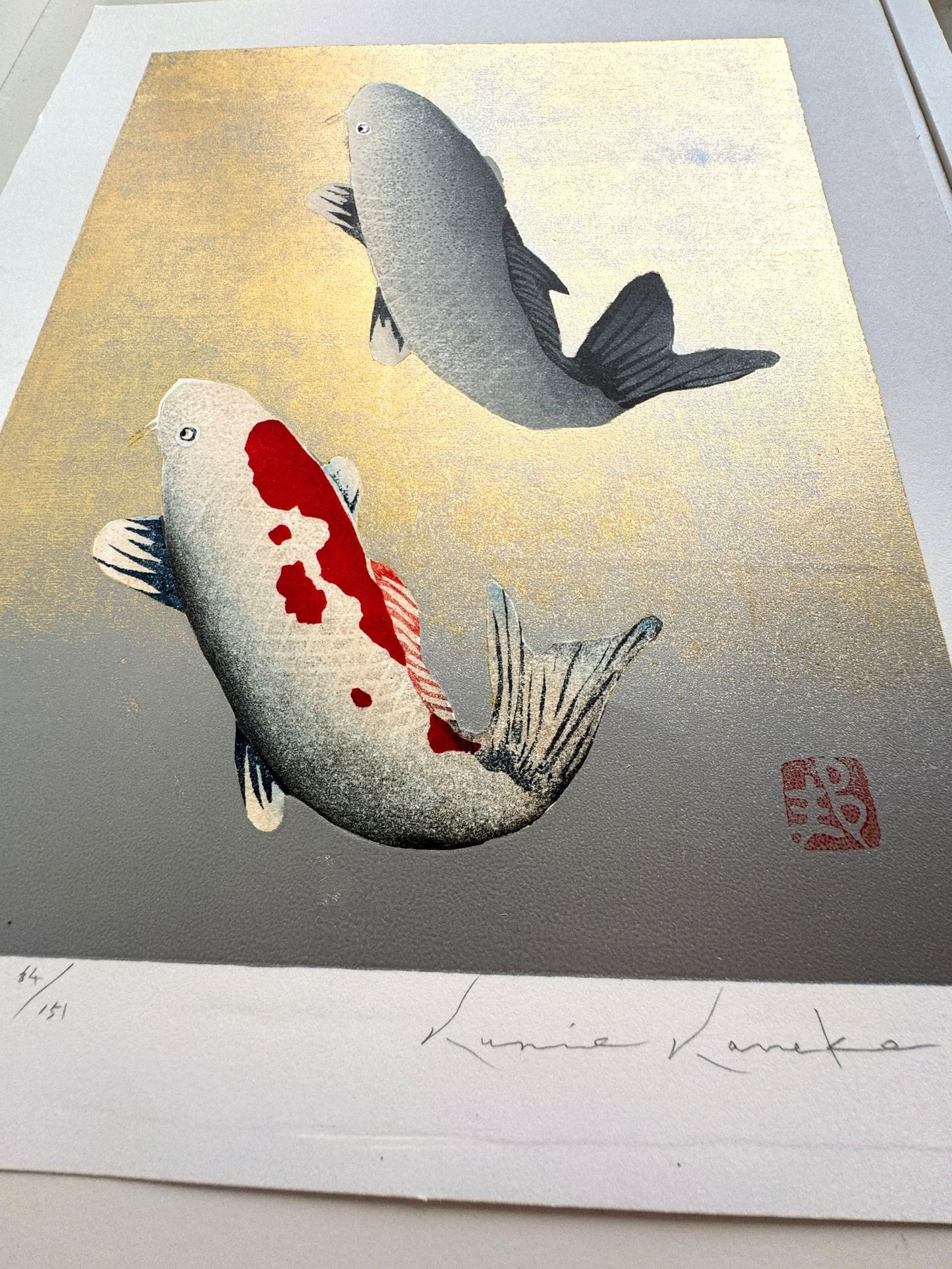 Estampe japonaise de Kunio Kaneko représentant deux carpes koï en sur fond doré et argenté, détail des reflets brillants