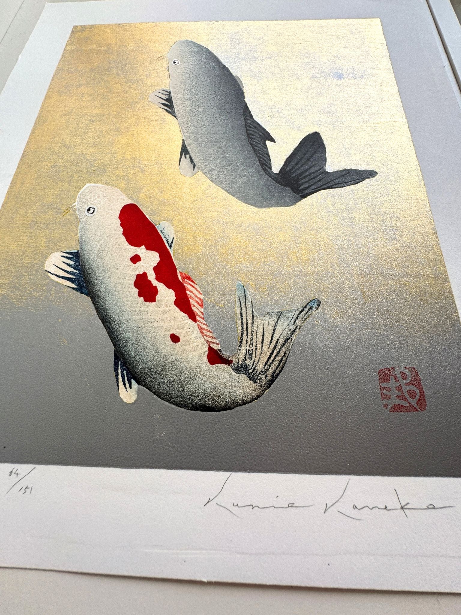 Estampe japonaise de Kunio Kaneko représentant deux carpes koï en sur fond doré et argenté, détail des reflets brillants