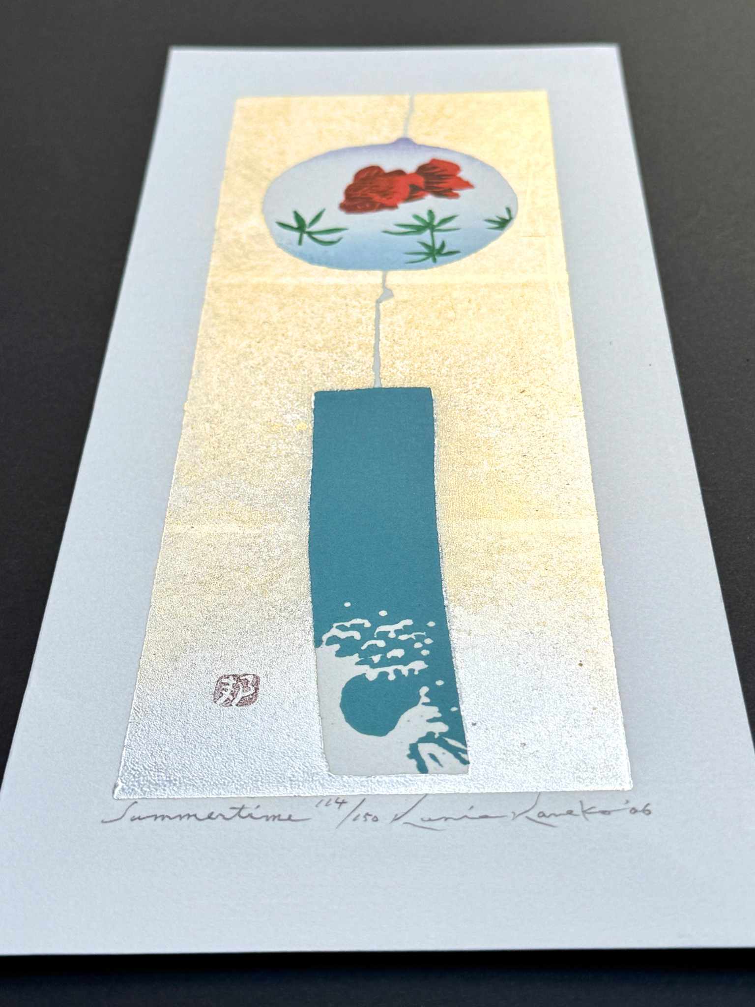 estampe japonaise contemporaine de Kunio Kaneko, une clochette furin avec poisson rouge et vague sur fond or et argent, de profil le reflet