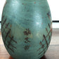 Kokeshi vintage japonaise de Yuji Kawase, au kimono vert orné de fleurs campanules colorées gravées et peintes, période Shōwa, vu en gros plan de la signature au dos