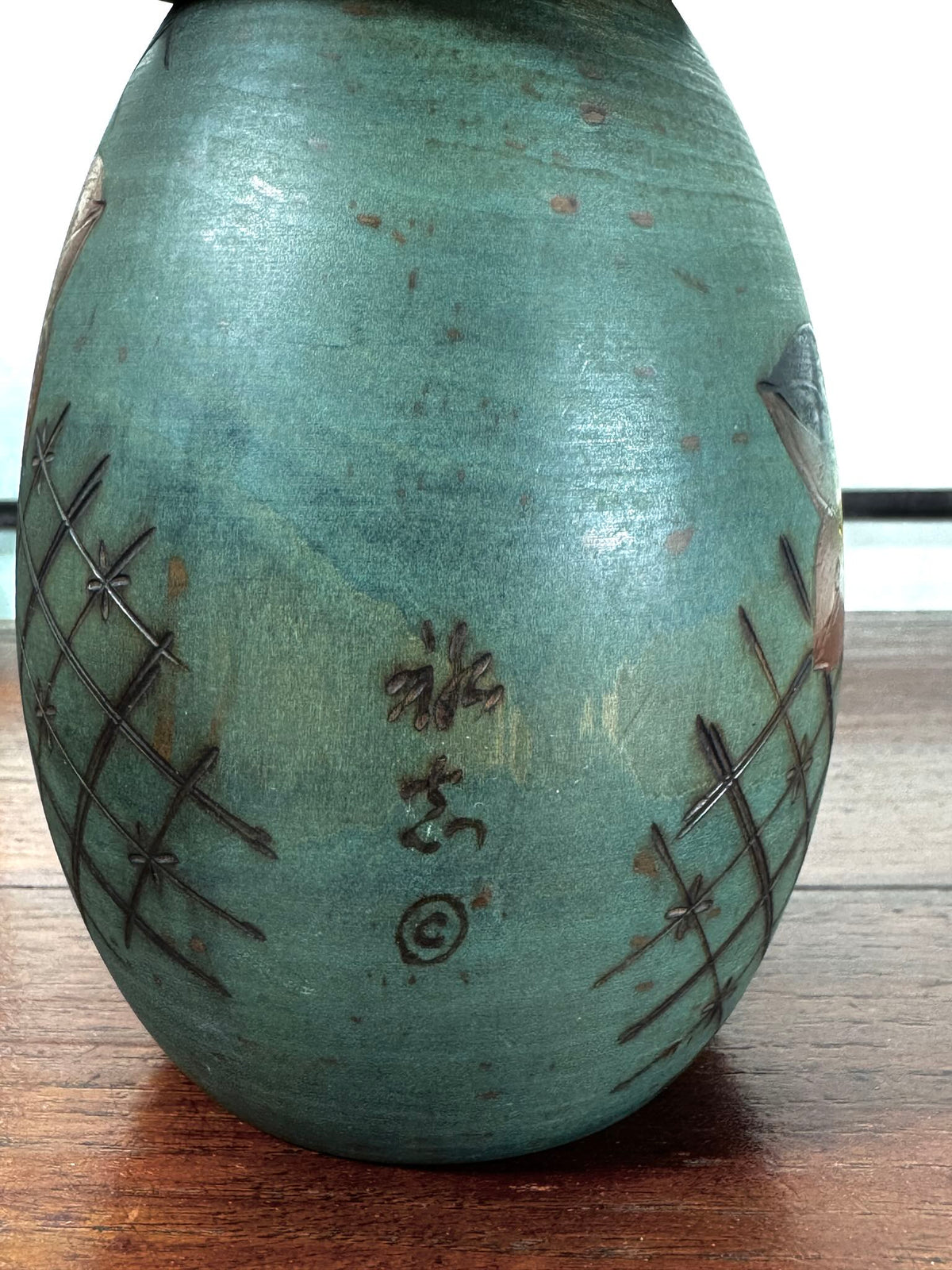 Kokeshi vintage japonaise de Yuji Kawase, au kimono vert orné de fleurs campanules colorées gravées et peintes, période Shōwa, vu en gros plan de la signature au dos