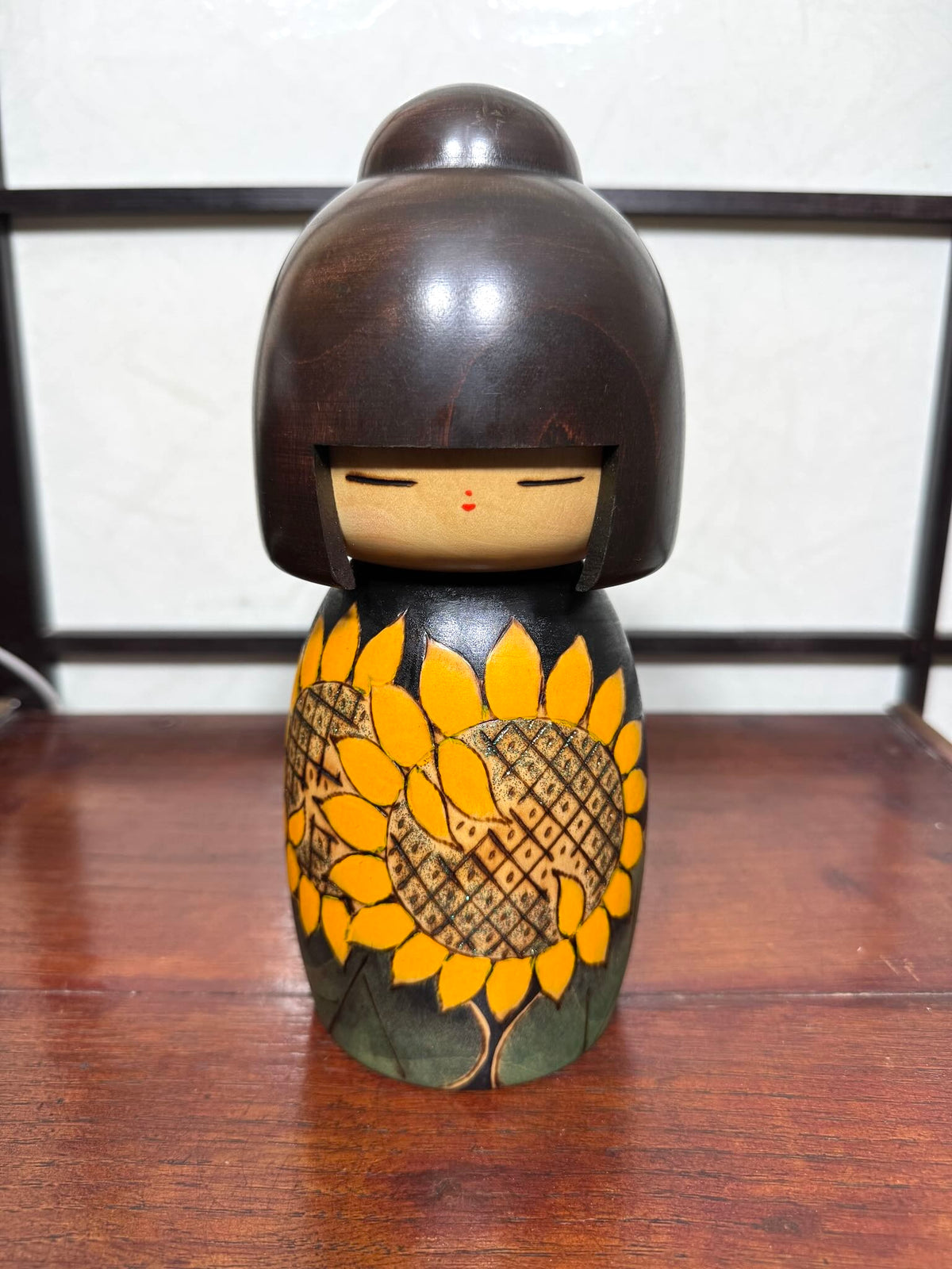 Kokeshi vintage japonaise de Yuji Kawase ornée de grands tournesols jaunes gravés et peints sur fond vert et noir.