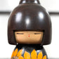 Kokeshi vintage japonaise de Yuji Kawase ornée de grands tournesols jaunes gravés et peints sur fond vert et noir, gros plan sur le visage