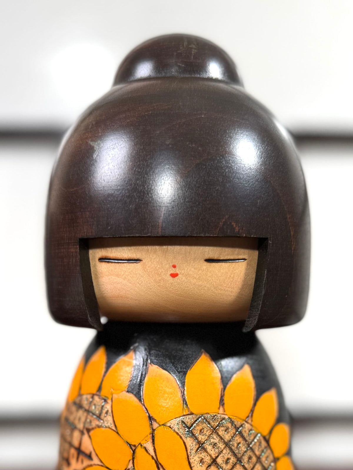 Kokeshi vintage japonaise de Yuji Kawase ornée de grands tournesols jaunes gravés et peints sur fond vert et noir, gros plan sur le visage