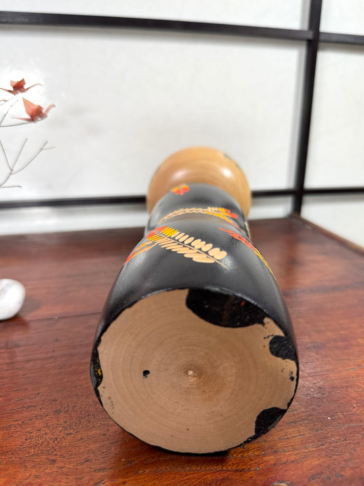 Grande kokeshi vintage de Yuji Kawase au corps noir décoré d’épis de riz beige, jaunes et rouges, Japon, période Shōwa. Le dessous