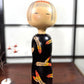 Grande kokeshi vintage de Yuji Kawase au corps noir décoré d’épis de riz beige, jaunes et rouges, Japon, période Shōwa.