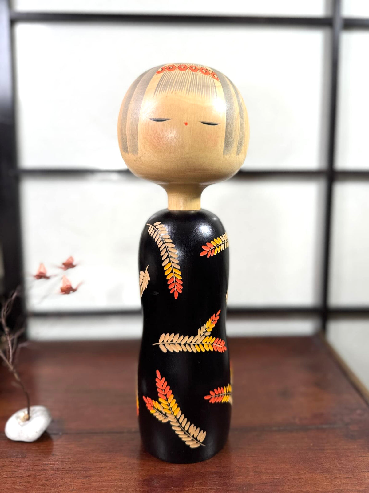 Grande kokeshi vintage de Yuji Kawase au corps noir décoré d’épis de riz beige, jaunes et rouges, Japon, période Shōwa.