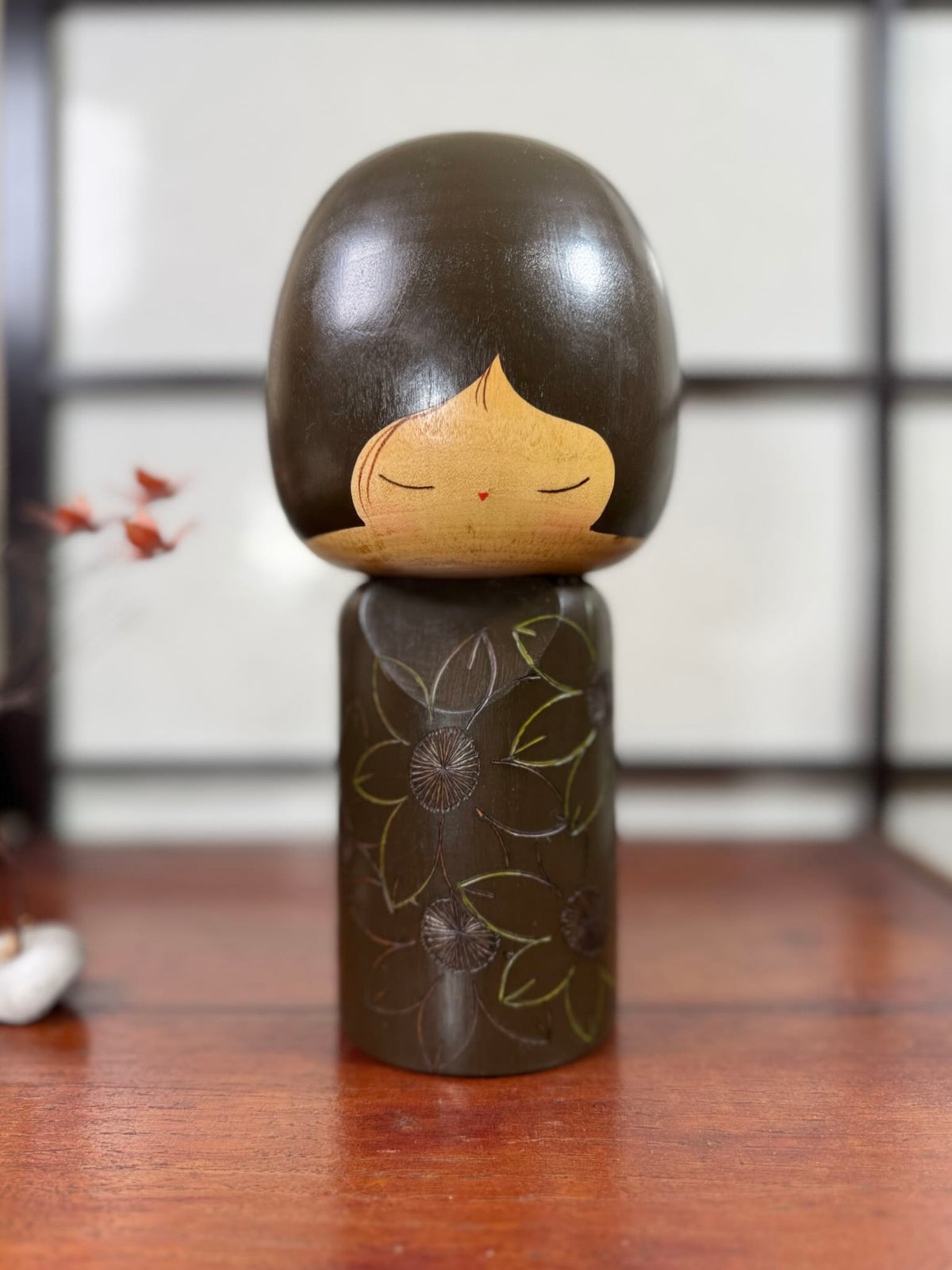 Kokeshi vintage de Yuji Kawase datée de 1980, caractérisée par une grande tête brune, un corps étroit et un décor de fleurs gravées.