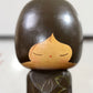 Kokeshi vintage de Yuji Kawase datée de 1980, caractérisée par une grande tête brune, un corps étroit et un décor de fleurs gravées, gros plan de la tête