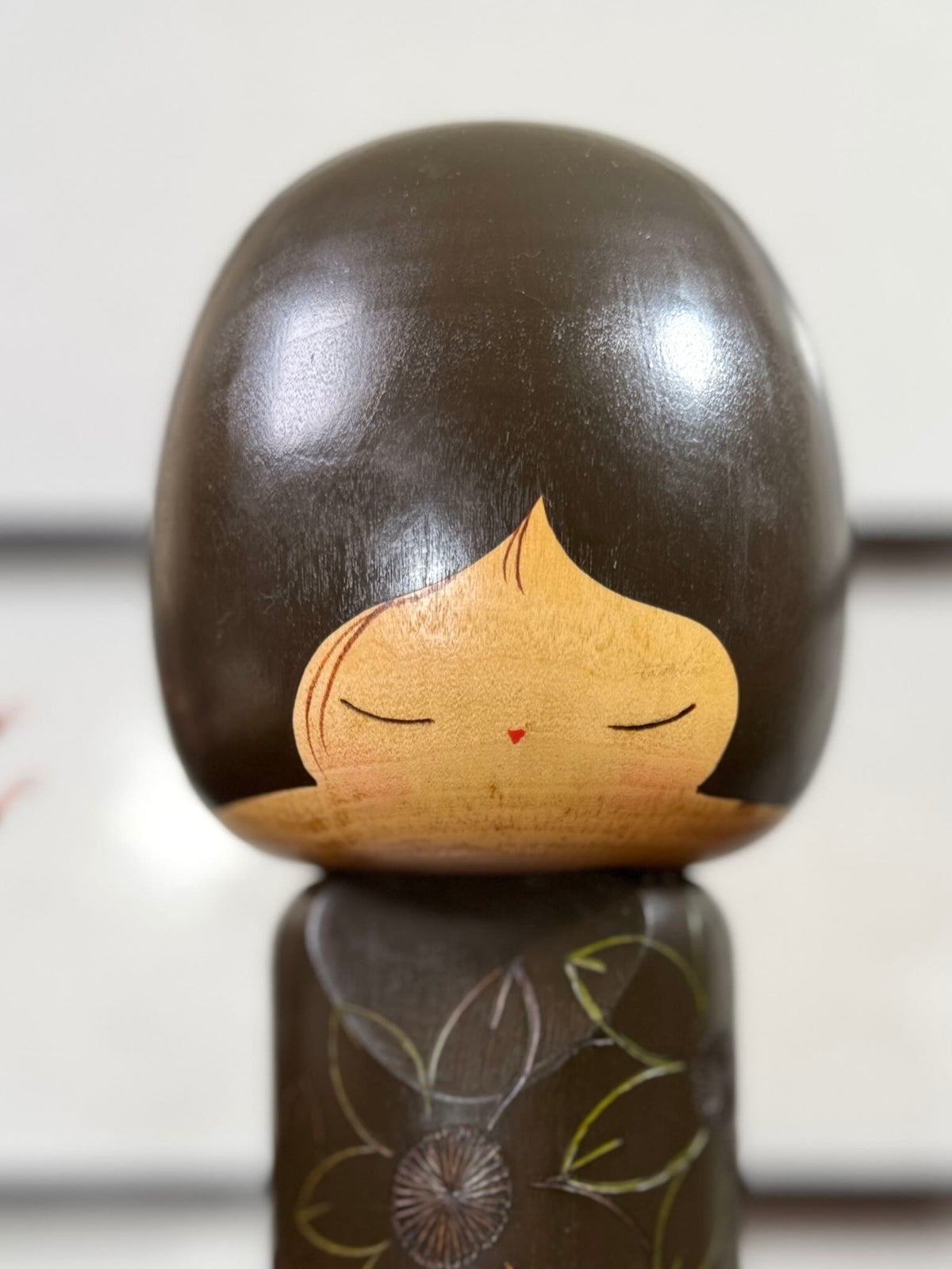 Kokeshi vintage de Yuji Kawase datée de 1980, caractérisée par une grande tête brune, un corps étroit et un décor de fleurs gravées, gros plan de la tête