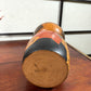 Kokeshi vintage de Yūji Kawase datée de 1977, en bois, à fleurs pyrogravées, grands aplats noirs et rouge brique en puzzle et visage aux yeux clos, le dessous