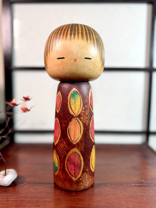 Kokeshi vintage Yuji Kawase décorée de vraies feuilles collées sur le bois et peintes couleurs d’automne, vu de face