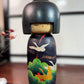 Kokeshi Yuji Kawase décorée de grues et de pins, vu de face