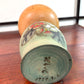 Kokeshi Yuji Kawase de 1979 à décor floral vert, rouge et blanc, la signature et la date au dessous