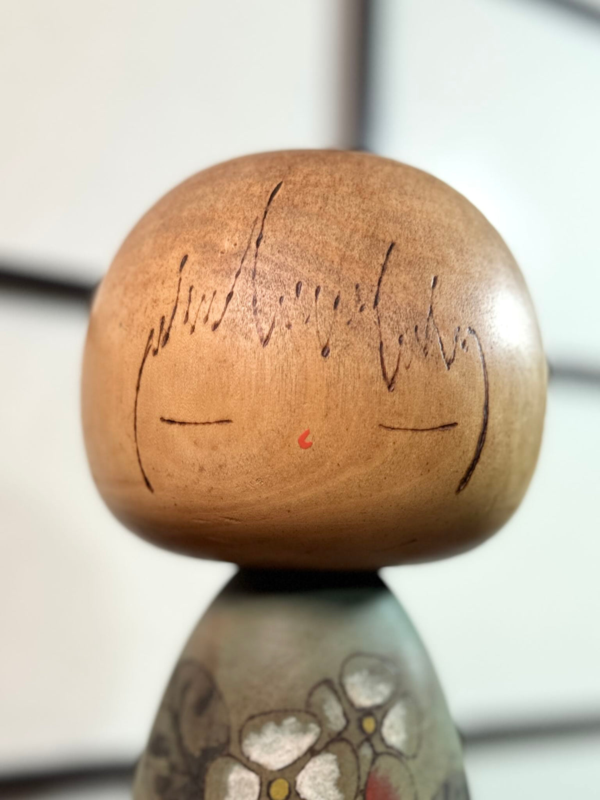 Kokeshi Yuji Kawase de 1979 à décor floral vert, rouge et blanc, gros plan sur le visage