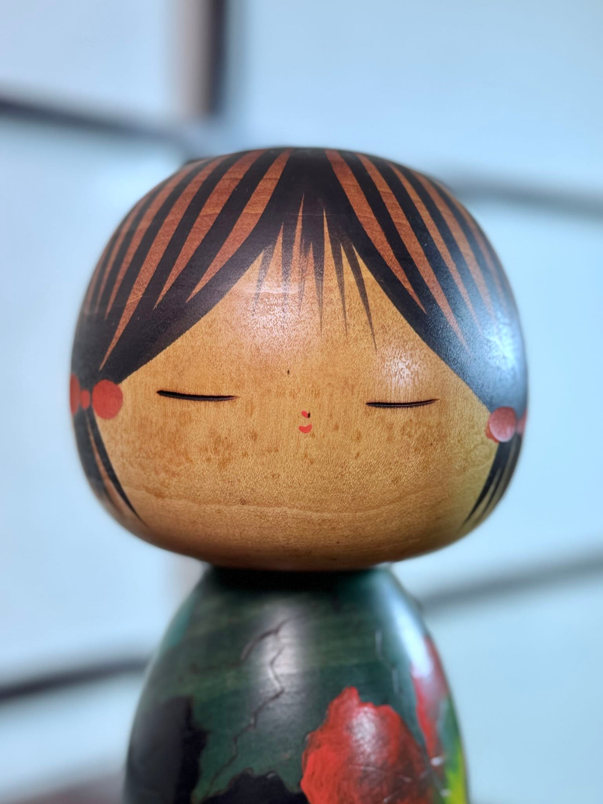 Kokeshi Yuji Kawase verte avec feuilles de vigne d’automne, gros plan sur le visage entouré de couettes