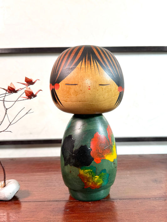 Kokeshi Yuji Kawase verte avec feuilles de vigne d’automne.