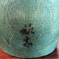 Kokeshi Yuji Kawase bleu-vert avec parapluies gravés et chignon, gros plan sur la signature.