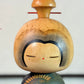 Kokeshi Yuji Kawase bleu-vert avec parapluies gravés et chignon, gros plan sur la tête