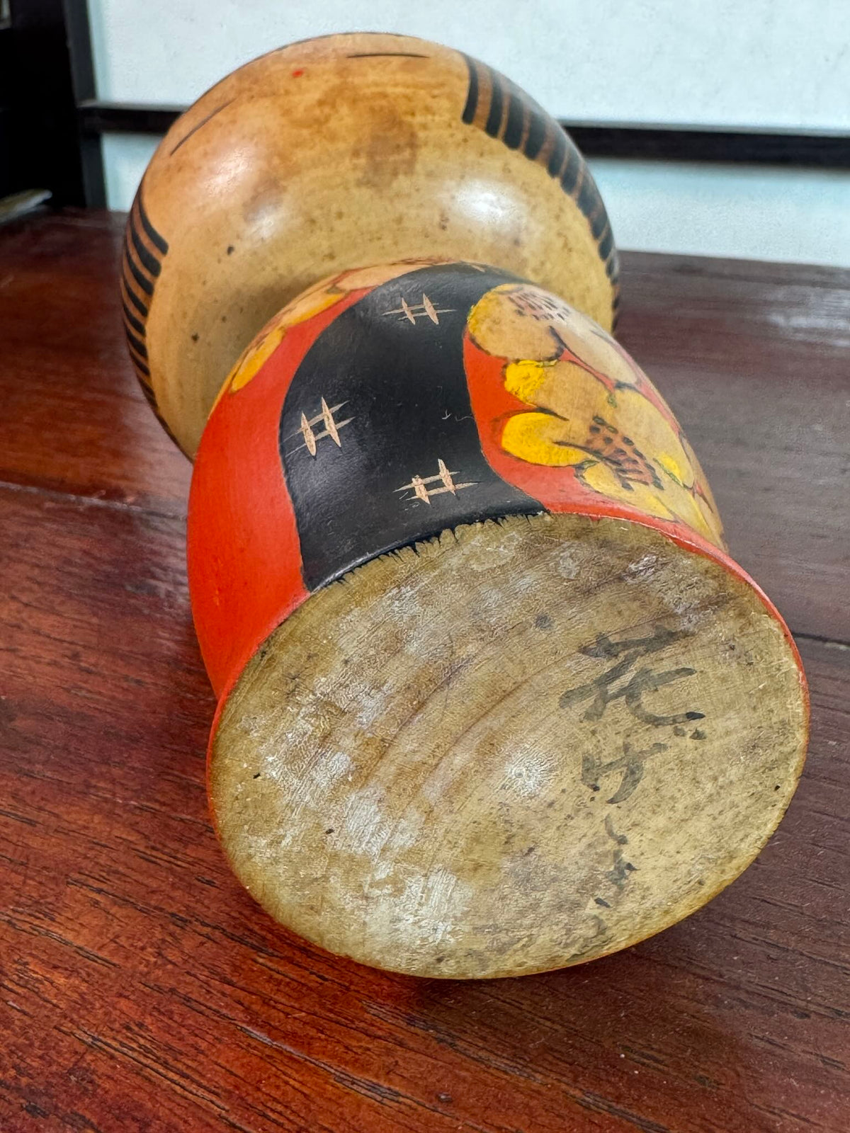 Kokeshi Yuji Kawase au kimono rouge fleuri et coiffure pointue., la signature au dessous