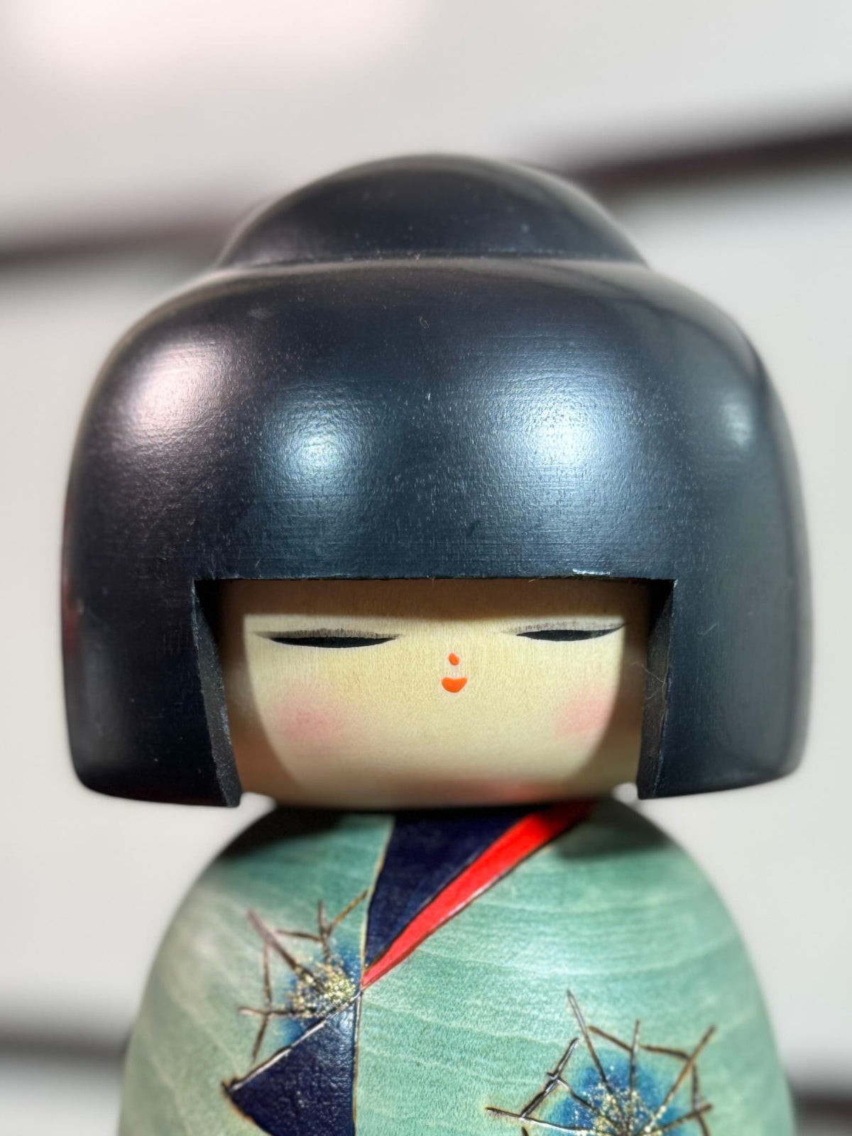 Kokeshi Yuji Kawase Asanoha au kimono vert et bleu gros plan sur le visage souriant