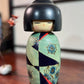 Kokeshi Yuji Kawase Asanoha au kimono vert et bleu.