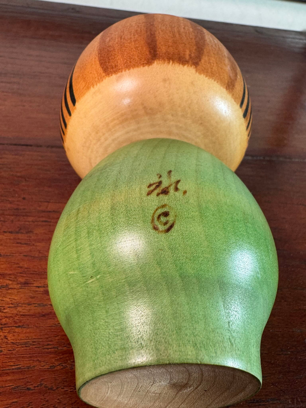 Kokeshi Yuji Kawase au kimono vert fleuri et coiffure à boules, la signature au dos