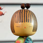 Kokeshi Yuji Kawase au kimono vert fleuri et coiffure à boules, gros plan sur le visage
