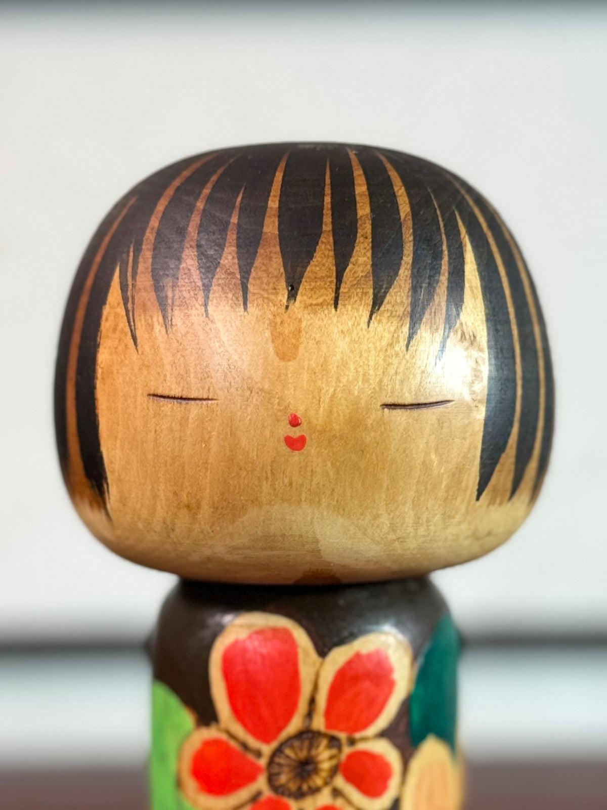 Kokeshi Yuji Kawase brune aux fleurs rouges et roses, gros plan sur le visage