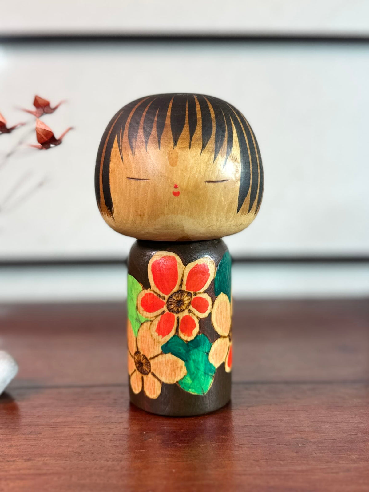 Kokeshi Yuji Kawase brune aux fleurs rouges et roses.