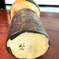 Kokeshi vintage de Yuji Kawase caractérisée par une grande tête brune, un corps étroit et un décor de fleurs gravées, la signature de l'artisan au dessous