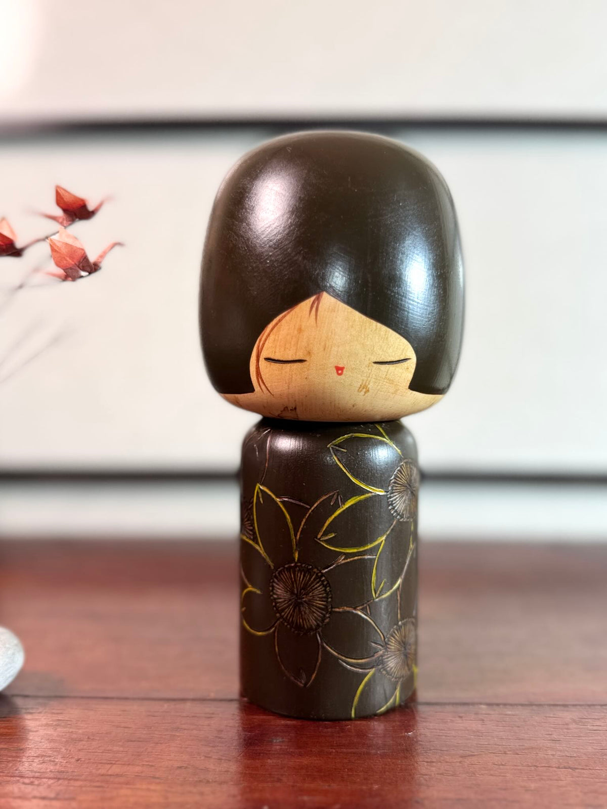 Kokeshi vintage de Yuji Kawase caractérisée par une grande tête brune, un corps étroit et un décor de fleurs gravées.