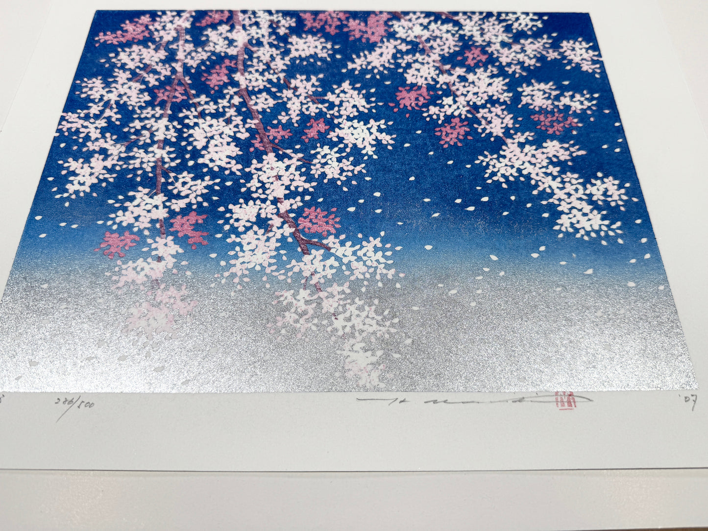 estampe japonaise contemporaine de Namiki Hajime cerisier en fleurs et pétales volant sur ciel bleu et argent, vu de 3/4