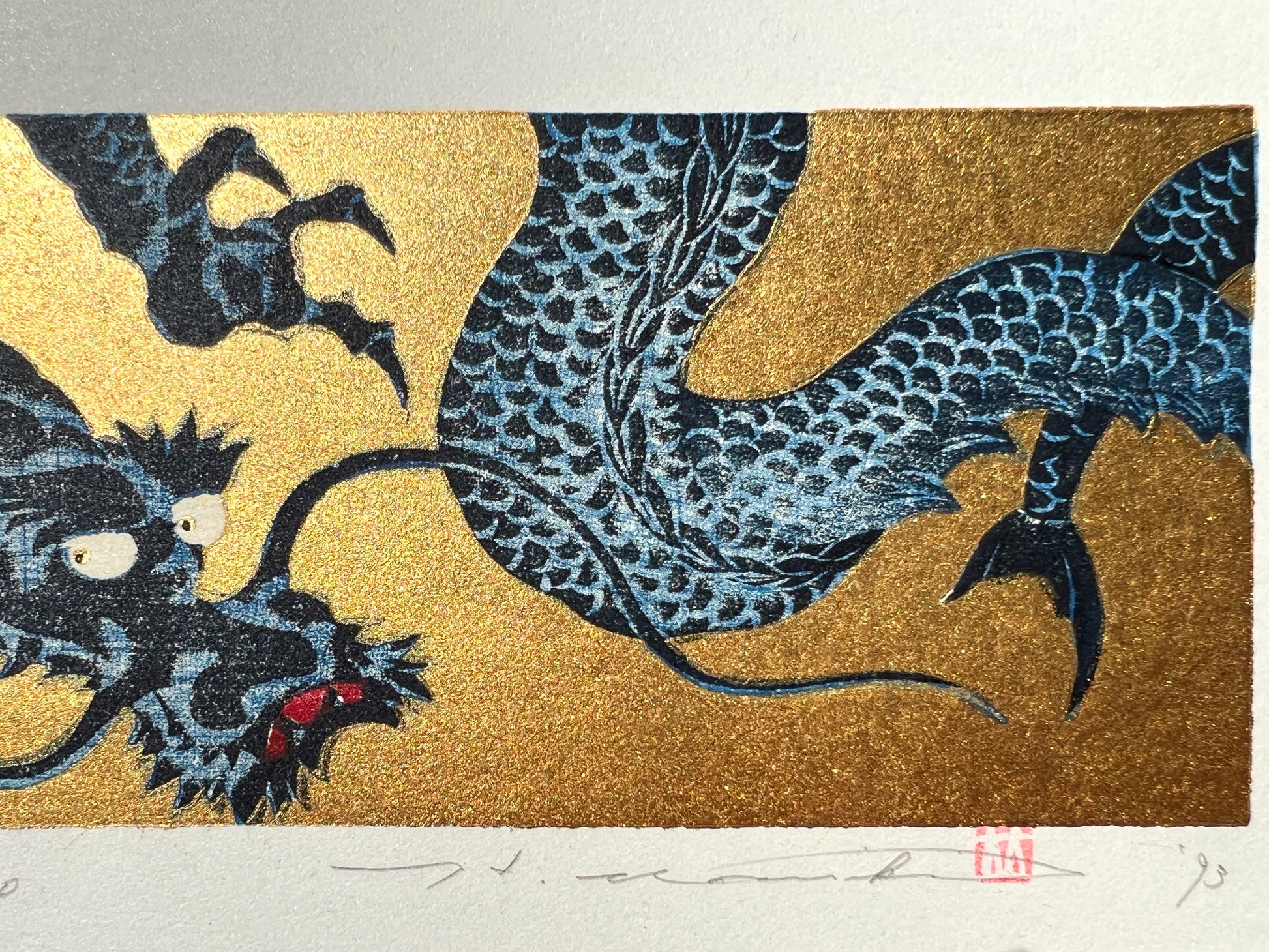 estampe japonaise dragon bleu gueule fermée sur fond or, la queue fourchue et signature de l'artiste