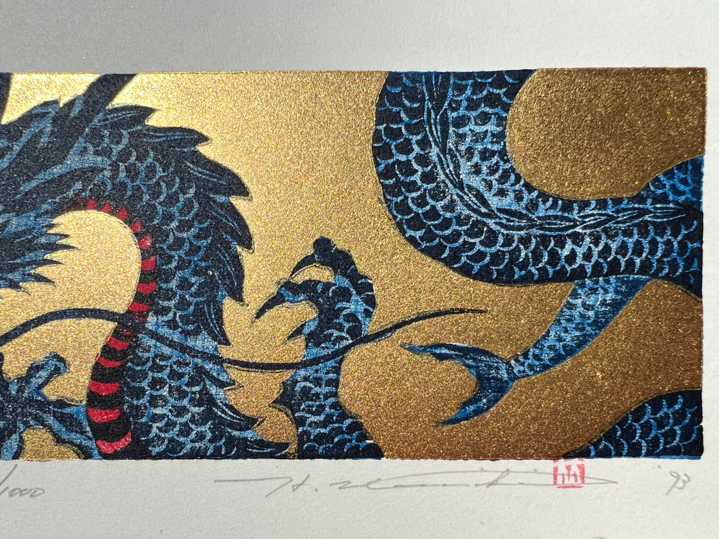 estampe japonaise dragon bleu sur fond or, gueule fermée, le corps et griffes, signature de l'artiste
