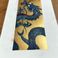 estampe japonaise dragon bleu sur fond or, gueule fermée, profil vue queue or scintillant
