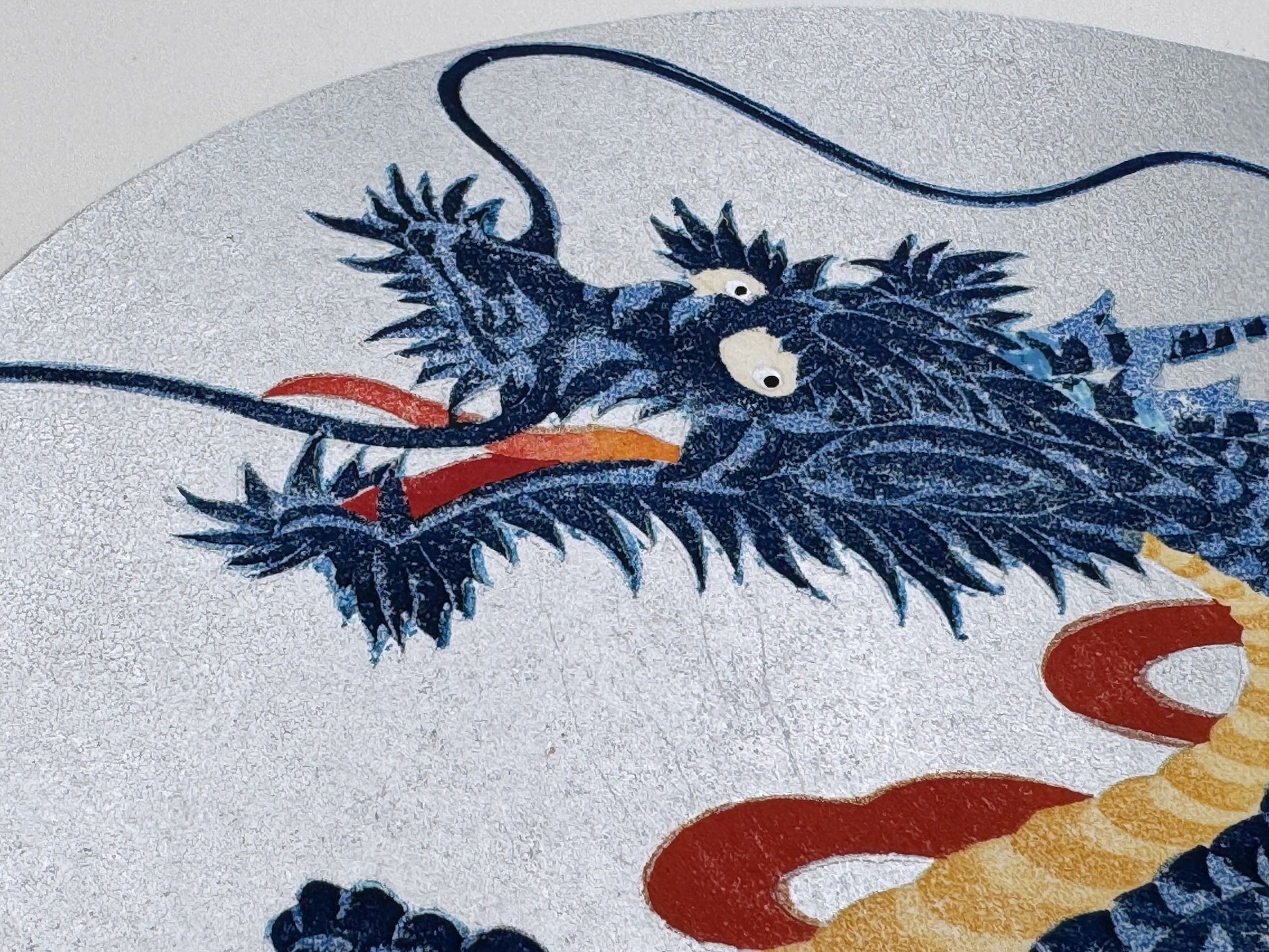 estampe japonaise dragon bleu gueule ouverte sur fond ovale argent, gros plan sur la tête du dragon et ses longues moustaches