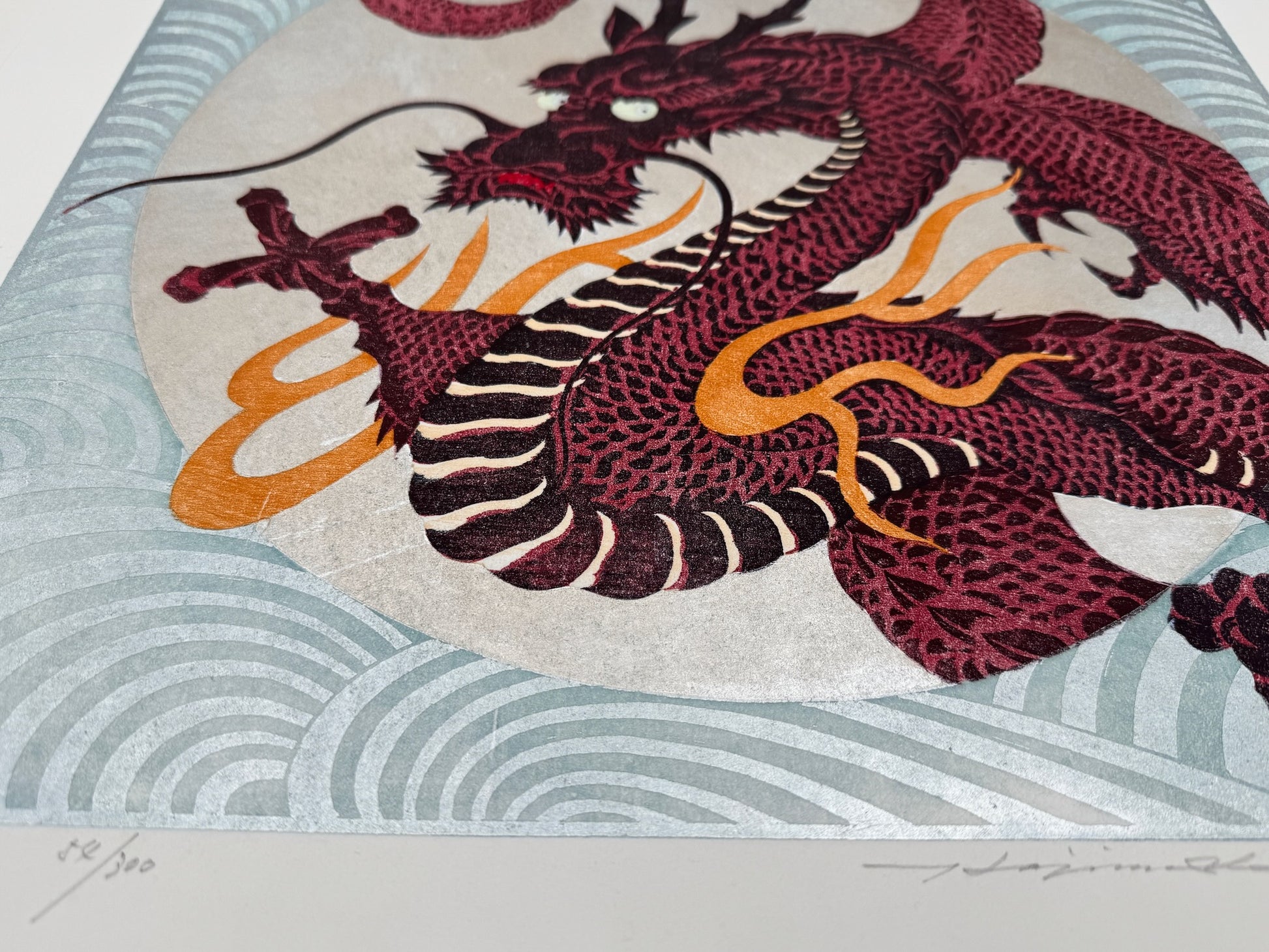 estampe japonaise dragon rouge sur fond argent à volutes, de profil