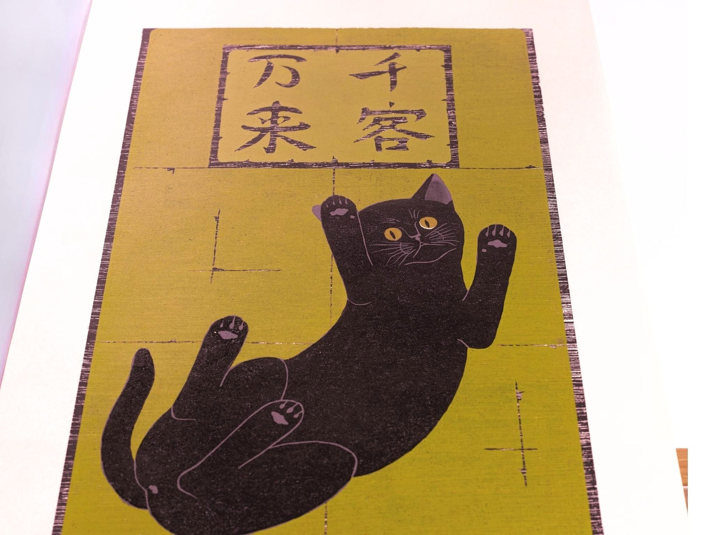 estampe japonaise de Nishida, un chat noir vu du dessous sur fond or avec calligraphie japonaise au dessus, vu de profil