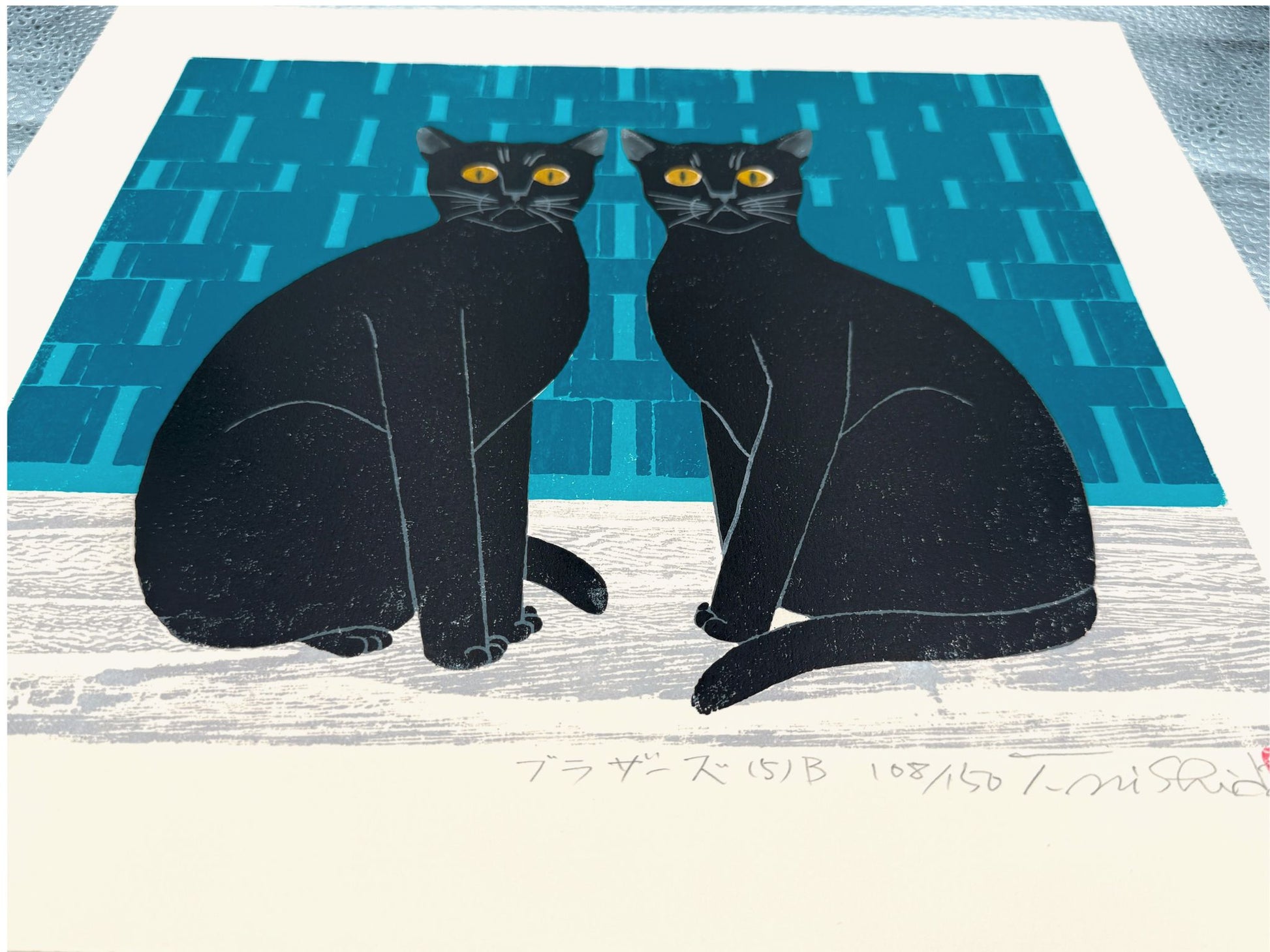 Estampe japonaise de Nishida représentant deux chats noirs sur fond bleu géométrique vue de profil