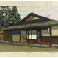 estampe japonaise contemporaine de Nishijima, un maison traditionnelle de potier avec petit banc rouge à l'entrée et cerisier en fleur en arrière plan.